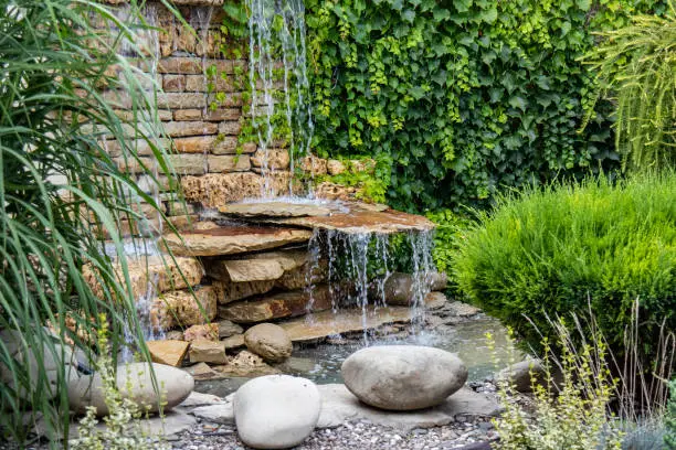 Photo of A small decorative waterfall in the Park or in the garden. Landscape design