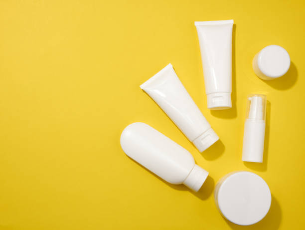 istock jar, bottle and empty white plastic tubes for cosmetics on a yellow background. Packaging for cream, gel, serum, advertising and product promotion 1348952110