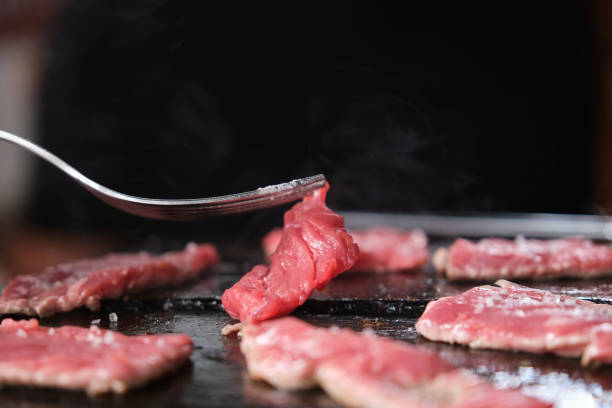 istock Cooking beef steak over hot stone in a restaurant. 1348957750
