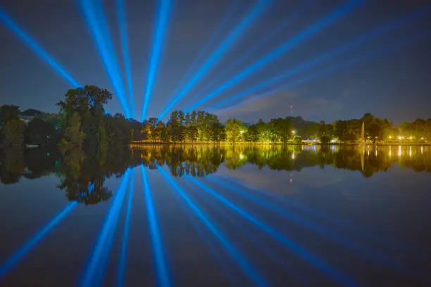 UFO behind the lake: night, town, rays, reflection.