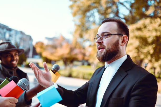 Hands of a woman standing behind a microphone at a public meeting, giving a speech, close-up, copy space