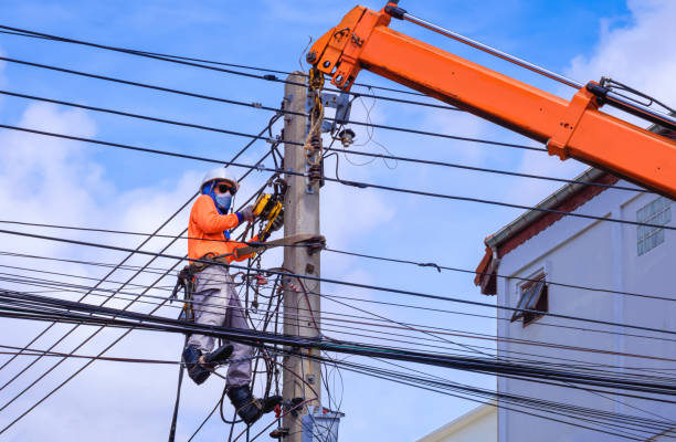 istock Electrician in protective mask with crane truck is installing cable lines and electrical system on power pole against blue sky 1348965509