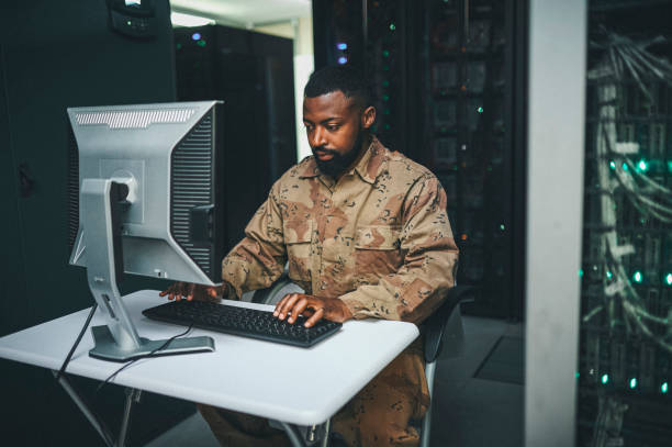 tiro de um técnico de ti masculino em uma sala de servidor e usando um laptop - marines camouflage camouflage clothing male - fotografias e filmes do acervo