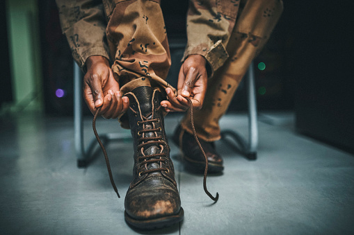 Shot of a soldier tying his boot shoelaces in the dorms of a military academy
