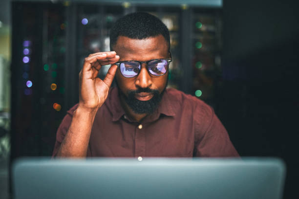 Shot of an male IT technician  in a server room and using a laptop Pulling an all nighter mainframe stock pictures, royalty-free photos & images