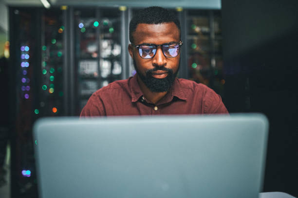 istock Shot of an male IT technician  in a server room and using a laptop 1348968296