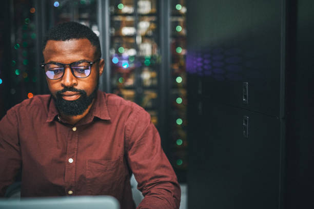 Shot of an male IT technician  in a server room and using a laptop Sorting out network issues data center stock pictures, royalty-free photos & images