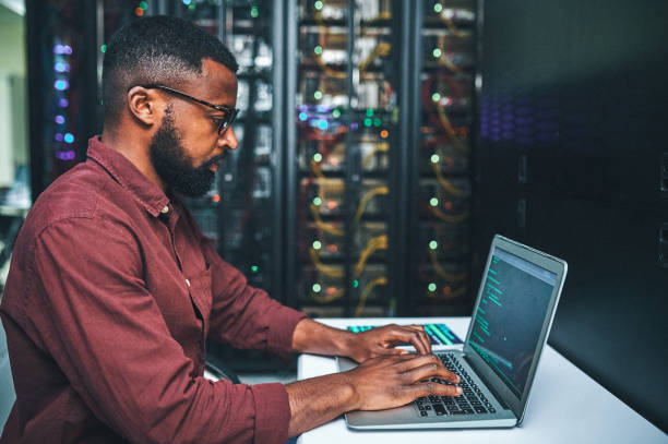 istock Shot of an male IT technician in a server room and using a laptop 1348968301