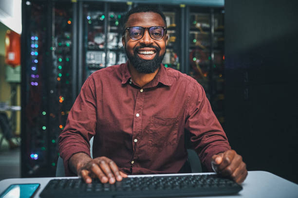Shot of an male IT technician  in a server room and using a laptop