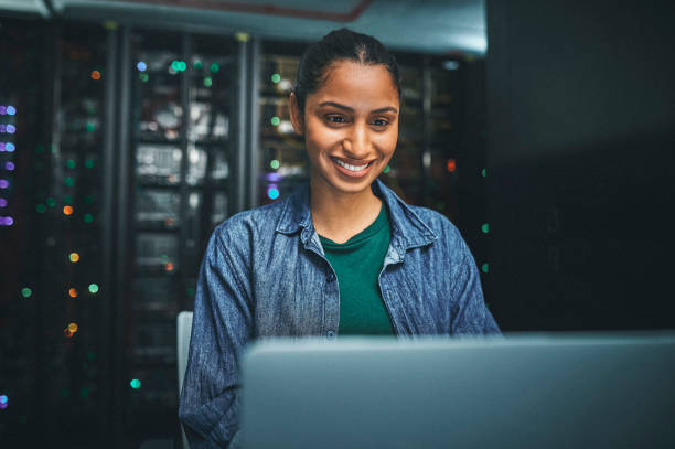 Shot of an female IT technician in a server room and using a laptop The art challenges the technology, and the technology inspires the art mainframe stock pictures, royalty-free photos & images