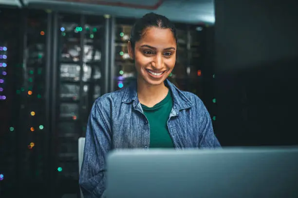 Photo of Shot of an female IT technician in a server room and using a laptop