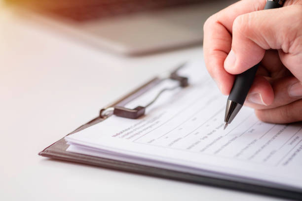 istock Image of Hand using writing pen with questionnaire or paperwork survey question filling 1348969788