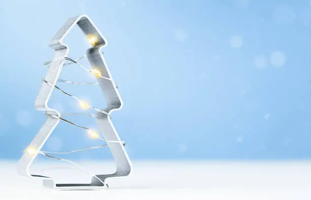 cookie cutter in the shape of a Christmas tree standing on a light blue background
