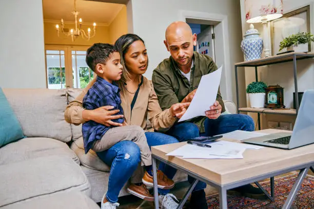 Photo of Shot of a young couple reviewing their finances while using their laptop