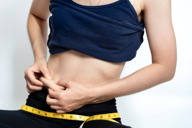 istock Woman wearing workout clothes and squeezing her belly fat with her hands on white background. Beauty or health concept. 1348971912
