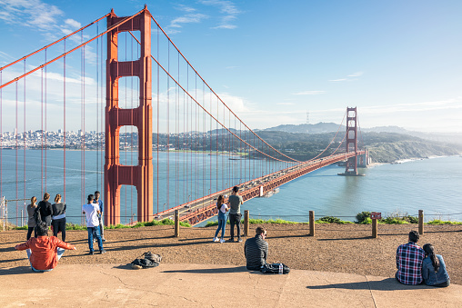 San Francisco, USA - Tourists visiting a viewpoint above the iconic Golden Gate Bridge, with the San Francisco skyline visible on the horizon at left.
