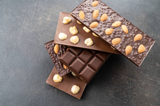 istock Chocolate bars with walnuts a tower on a black background. Milk and Dark Chocolate With Almonds and Hazelnuts Isolated 1348974133