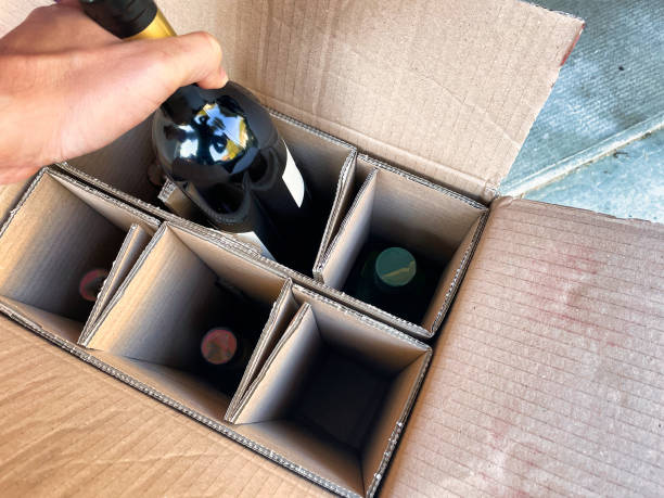 delivery of bottles of wine in box Menthon saint Bernard, France - October 16 2021: a person is taking a bottle of wine ordered on the internet out of a delivery box wine shipping stock pictures, royalty-free photos & images