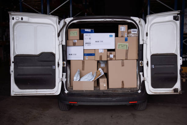 istock Delivery man working on digital tablet while organising packages for shipment in a van with his coworker. 1348975475