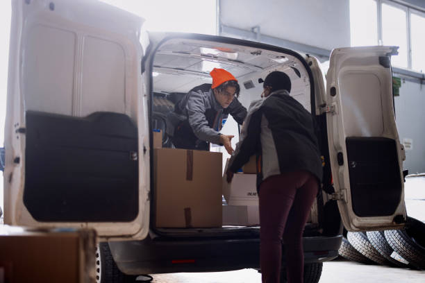istock Diverse team of delivery drivers moving packages from distribution warehouse to van 1348975806