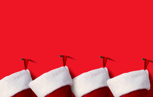 A row of Christmas stockings haning from a red background.