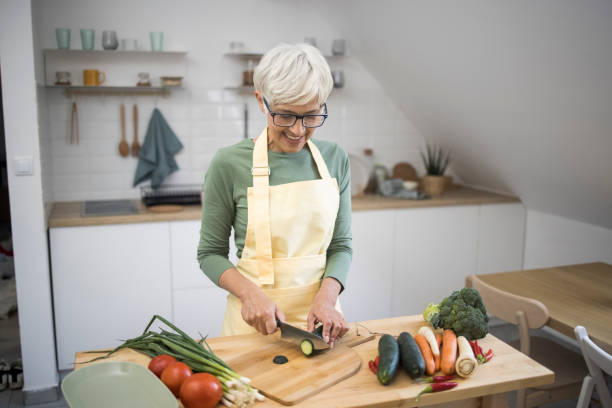 istock Old woman preparing food in kitchen 1348976824