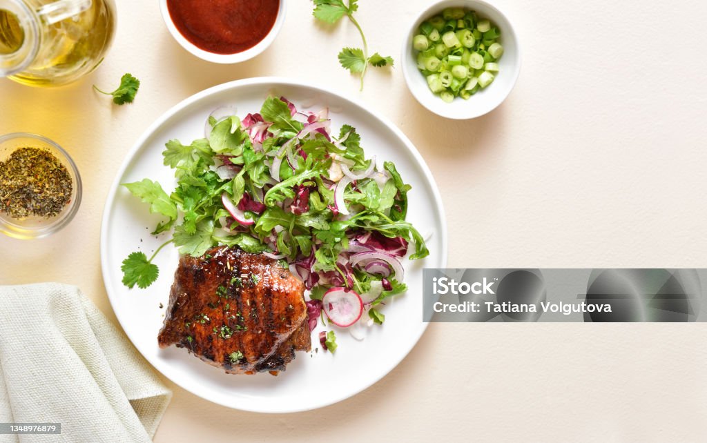 Roasted pork steak Roasted pork steak with salad from fresh vegetables over light stone background with copy space. Top view, flat lay, close up High Angle View Stock Photo