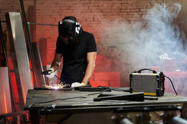 istock a masked welder in a workshop works with an inverter welding machine 1348978957