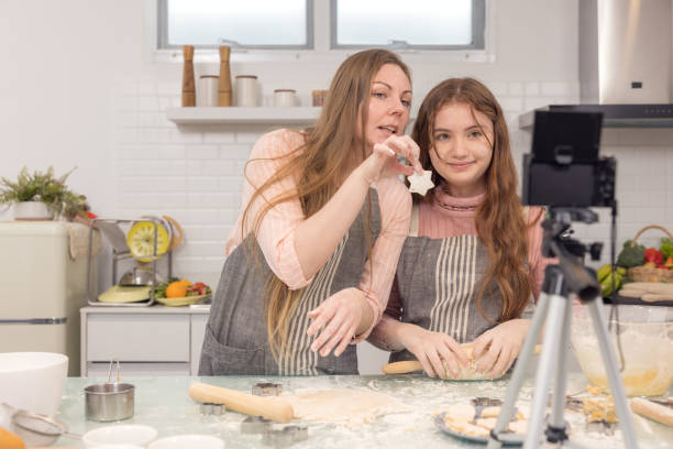 istock With a live digital camera in the kitchen, mother and daughter smile and have fun while preparing biscuit dough together, daughter learning how to make cookies with her mother. 1348979401