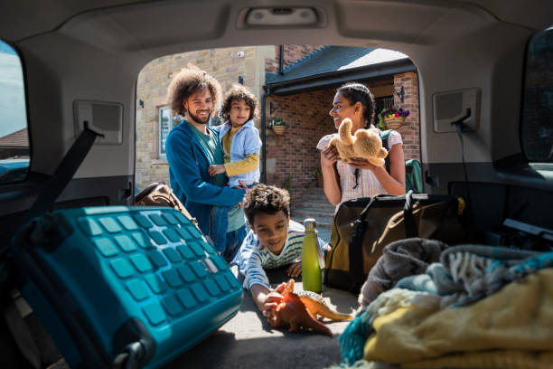 Don't Forget the Toys Medium shot with camera placed inside of a car showing a family unpacking a car boot, getting their bags and the children's toys when they arrive at the lodge they're staying on during a staycation in the Northeast of England together. The father is carrying one of their sons. man with teddy bear stock pictures, royalty-free photos & images