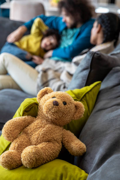 Close up focus on a teddy sitting on a soda with a family cuddling in the background while on staycation in the North East of England.