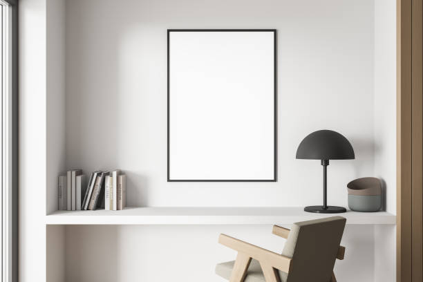 istock Niche desk with empty framed canvas on white bedroom wall 1348981942