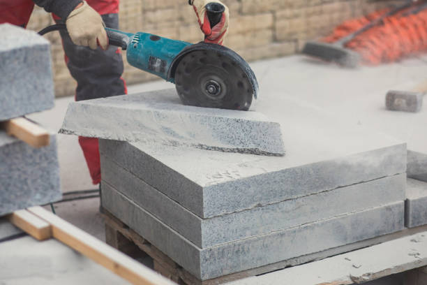 istock Process of cutting, sawing and grinding granite cement tile slab with cutting machine, worker with circular saw during new walkway asphalt pavement works, worker cuts ceramic concrete tile 1348983363