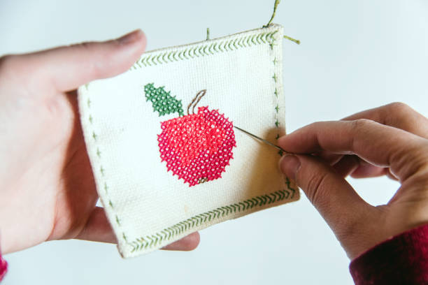 point de croix d’une figure de pomme sur un morceau de tissu. - embroidery cross stitch needle sewing photos et images de collection