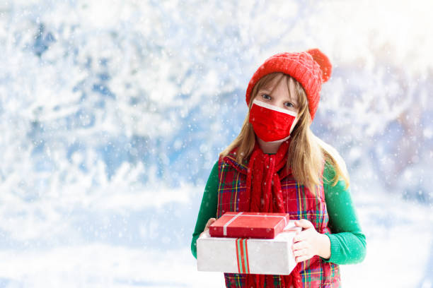 istock Child in face mask with Christmas present. 1348985892