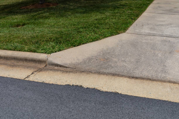 istock Specially formed concrete curb turning into a concrete drive, manicured grass and asphalt street bed 1348987825