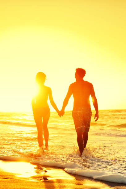 istock Beach couple holding hands together at sunset 1348987859