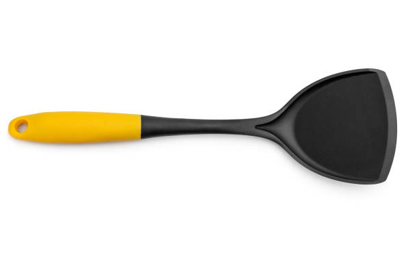 istock Black plastic spade with a yellow handle for frying pan on white background. 1348992712