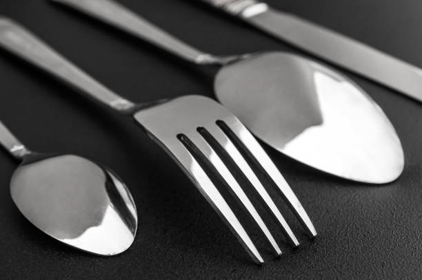 istock Fork, knife and spoon on black background. Close up. 1348992729