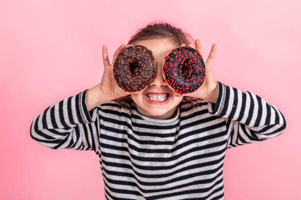 istock Funny little girl with donuts on a pink background. 1348993241