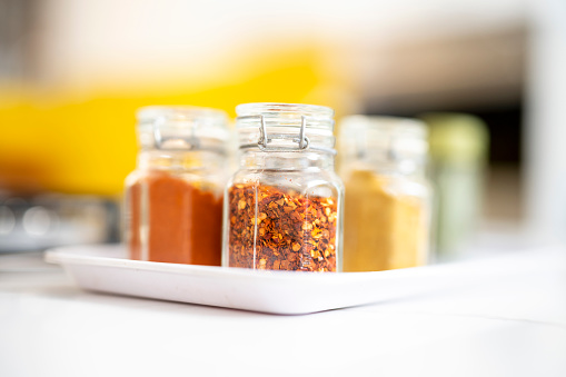Reusable glass jars fill of different spices on kitchen counter