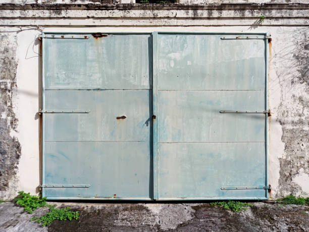 puerta doble metálica vieja, cerrada y oxidada sobre muro de hormigón corroído. arquitectura y construcción en las indias occidentales francesas. - wood shutter rusty rust fotografías e imágenes de stock