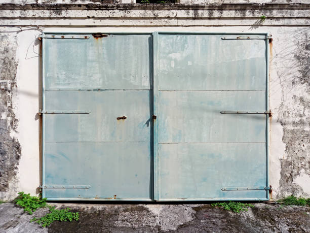 stare, zamknięte i zardzewiałe metalowe podwójne drzwi na skorodowanej ścianie. architektura i budownictwo we francuskich indiach zachodnich. - wood shutter rusty rust zdjęcia i obrazy z banku zdjęć