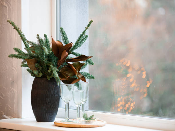 istock Winter decor composition - spruce branches and dried leaves in a brown vase on a window sill. 1349004869