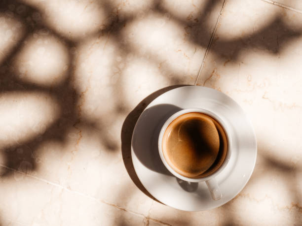 Cup of aromatic coffee standing on an empty table Cup of aromatic coffee standing on an empty table. View from above, outdoor, close-up. Vacation and travel concept coffee crop stock pictures, royalty-free photos & images
