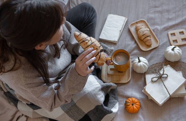 istock Young woman drinking coffee with a croissant in bed, top view. 1349006278