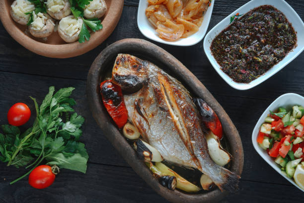 poisson frais sur une planche de bois noire. daurade crue non cuite sur assiette noire. - mediterranean diet photos et images de collection
