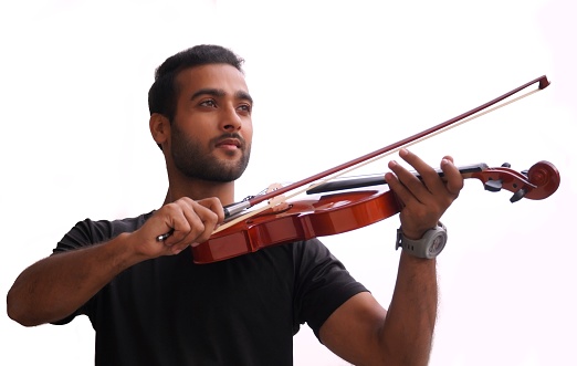 Directly above view of caucasian young male violinist standing in front of white background wearing businesswear who is excited and holding violin