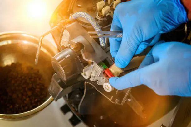 A repairman repairs a broken coffee maker with tool