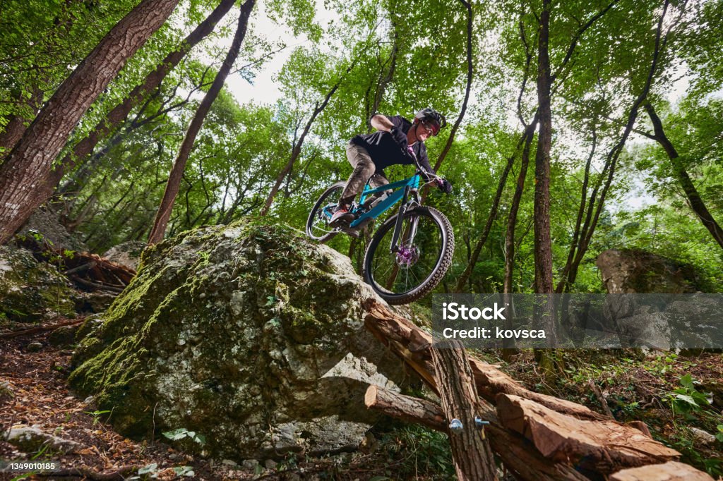 Enduro biker on a self-constructed challenging trail in the woods Enduro bike with full suspension and protective sports gear and equipment on a steep north face on a dirt path Mountain Bike Stock Photo
